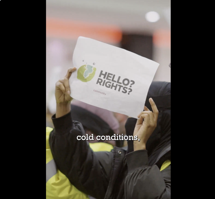 A screenshot from the video with a worker carrying a sign (Hello?Rights?)